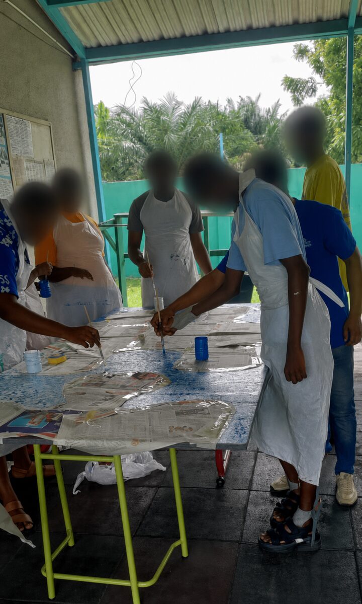 Elorm working closely with a child during a hands-on art activity.